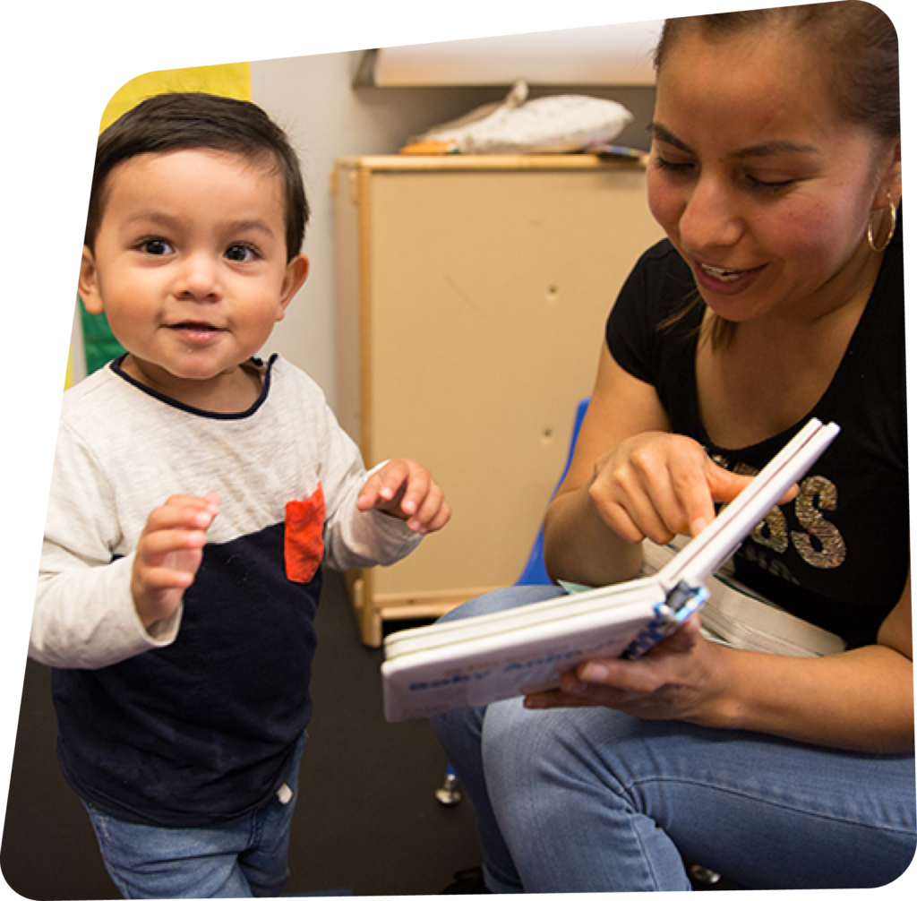 Educator reading a book to a toddler aged boy