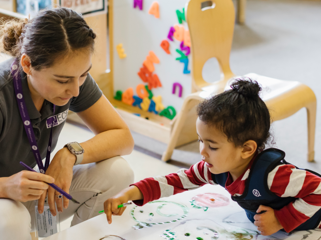 teacher playing with child at craft table