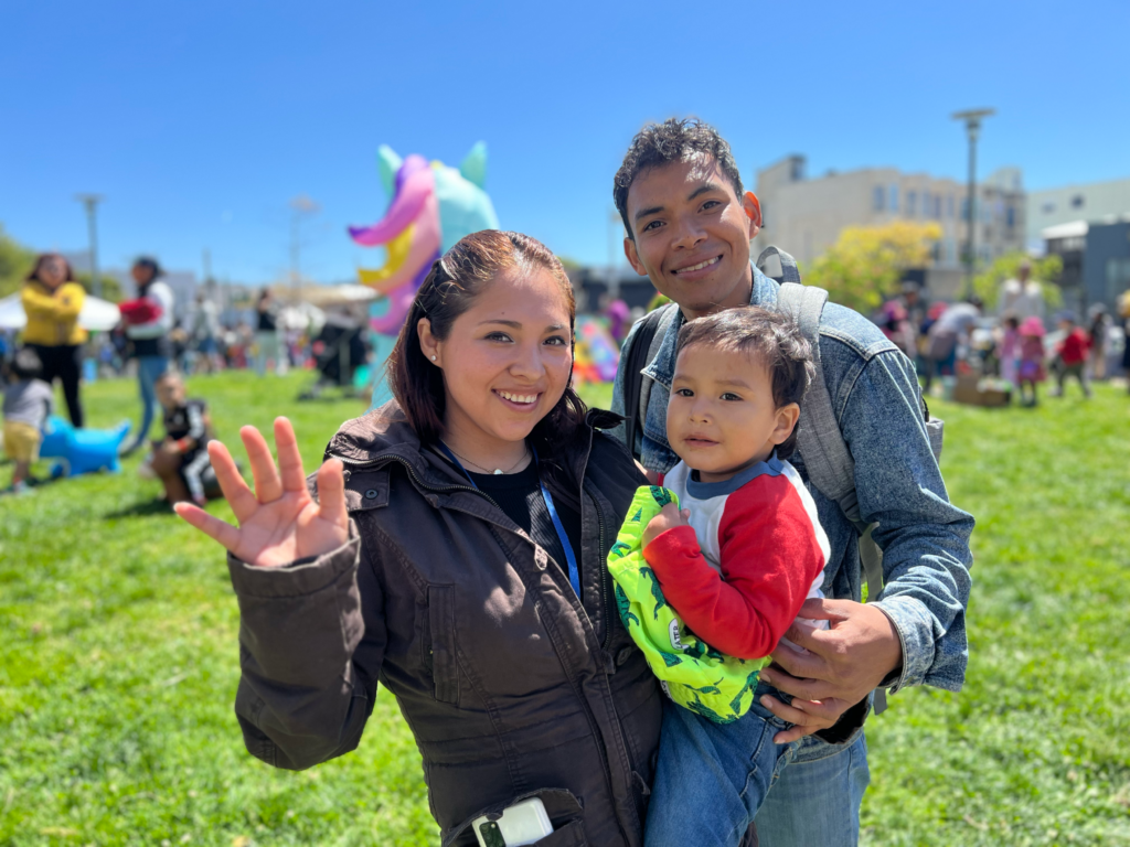 mother father and young child smiling outside