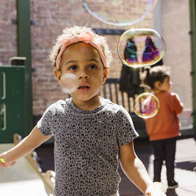 young girl playing with bubbles outside